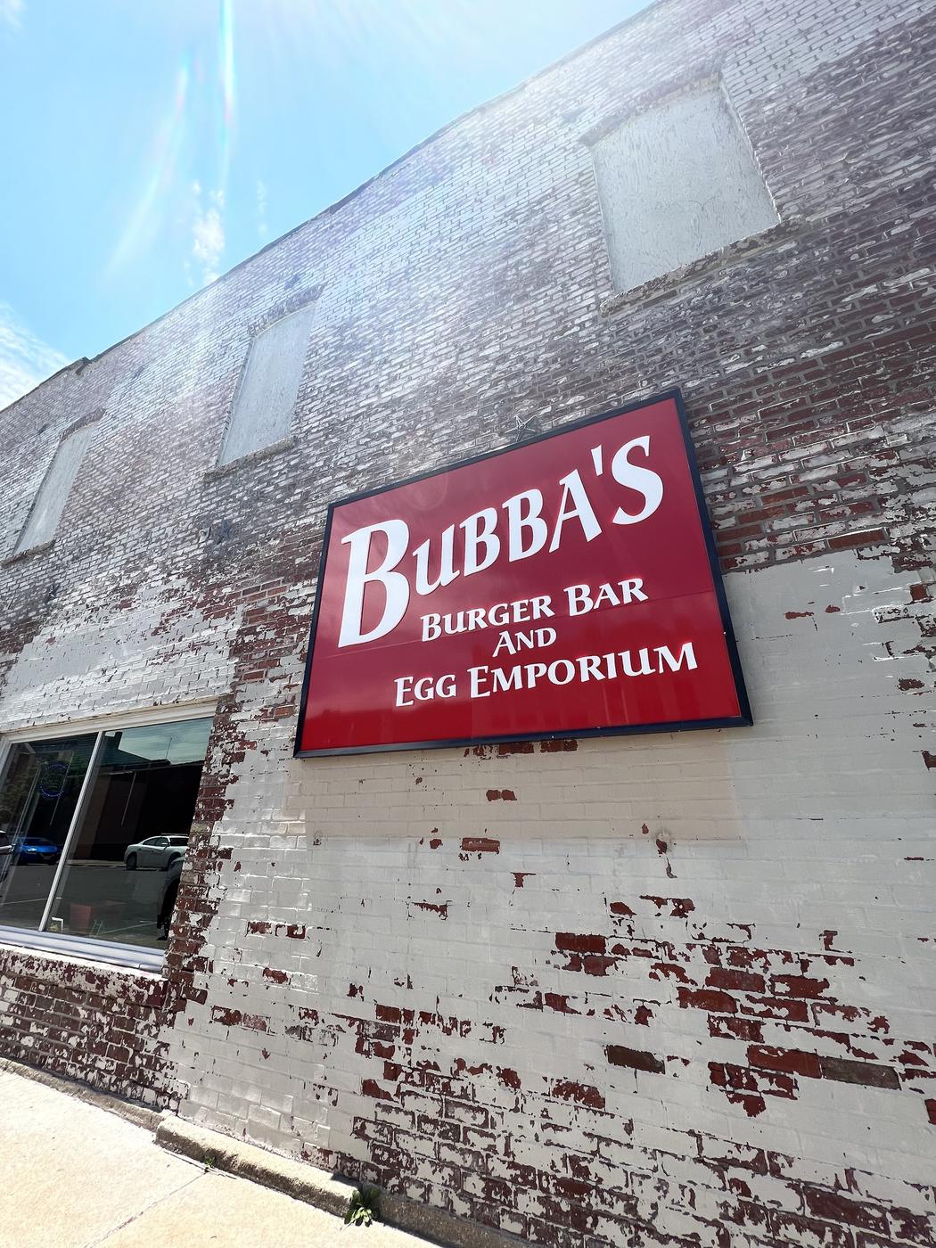 The red Bubba's Burger Bar and Egg Emporium sign mounted on the whitewashed brick wall of the building