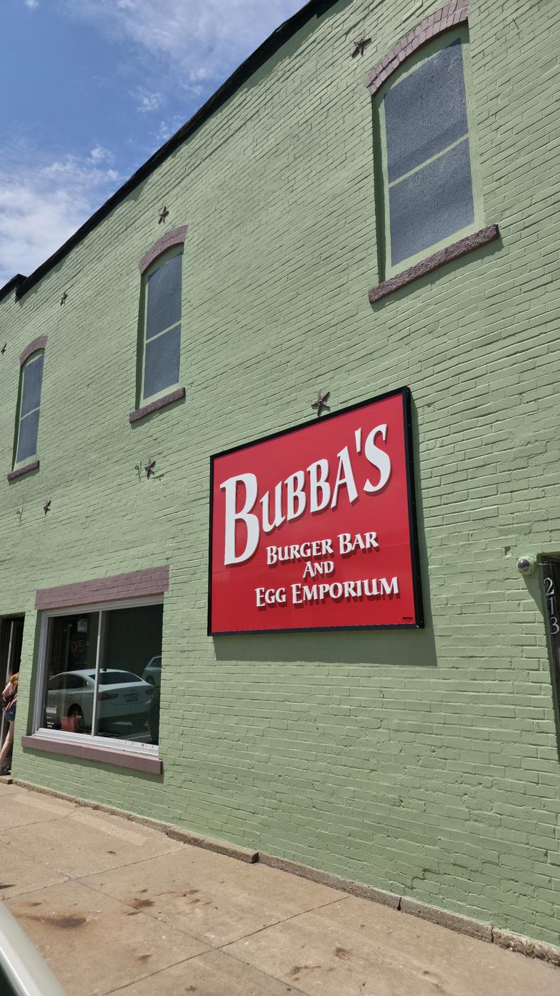 The sage-green brick front of Bubba's with its red sign reading Bubba's Burger Bar and Egg Emporium